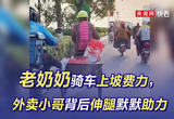 老奶奶骑车上坡费力，外卖小哥背后伸腿默默助力